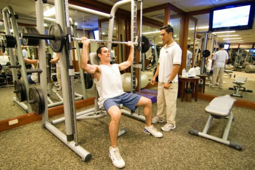 Отель Marco Polo Davao Экстерьер фото A personal trainer assisting a client with a weight training exercise